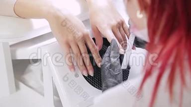 美容店里戴着手套的美甲女士在涂胶前用指甲锉钉给客户指甲